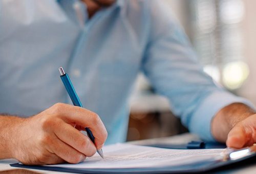 Un hombre escribiendo información importante en un pedazo de papel - Compucad México